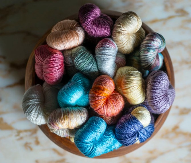 Colorful, shimmery yarn in a wooden bowl