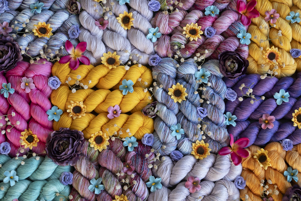 A grid of hand-dyed yarn in shades of golden yellow, violet, hot pink, aquamarine, pale lavender, pink, blue and more