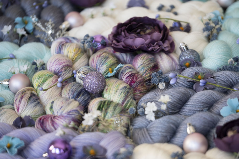 A close-up image of colorful hand-dyed yarn in shades of lavender, pink, cream, aquamarine and more