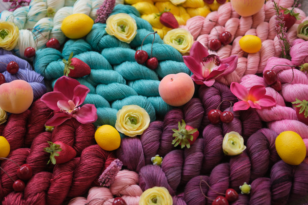 A close up photo of bright, saturated, hand-dyed yarns in turquoise, red, purple, pink and more